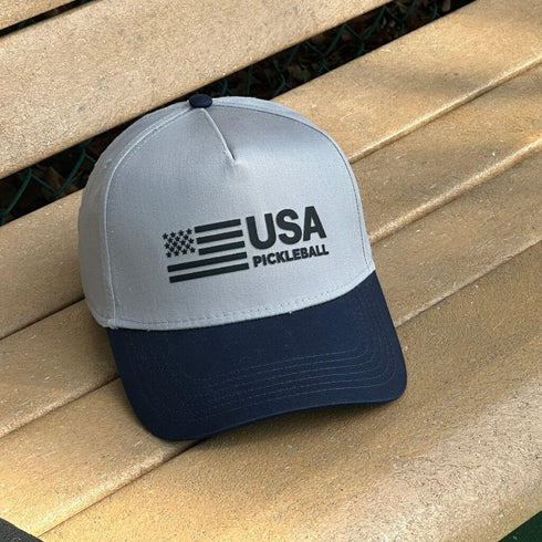 Gray and navy cap with 'USA Pickleball' logo on a wooden surface
